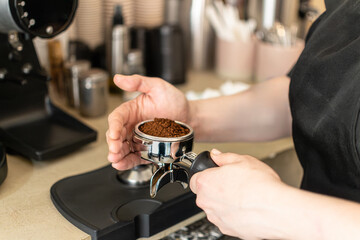 Barista holding a portafilter filled with freshly ground coffee before tamping in a specialty coffee shop