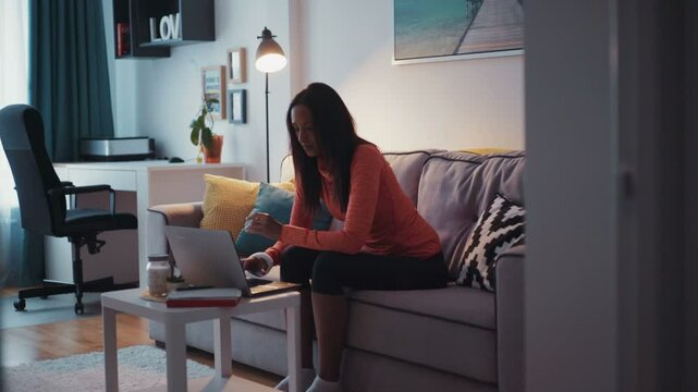 A young beautiful mulatta girl ends up working on a laptop taking the phone and goes. At home. Feels happy. Contemporary design. Shot on RED Epic Camera.