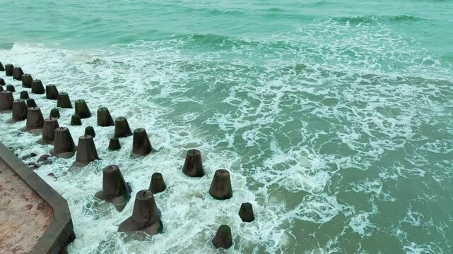 Calm waves roll towards resilient concrete structures along the coast The cloudy sky reflects a tranquil ambiance making it a serene seaside view