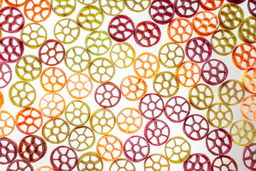 Background with texture dry italian pasta Rotelle. Different flavors and colors: egg, spinach,...