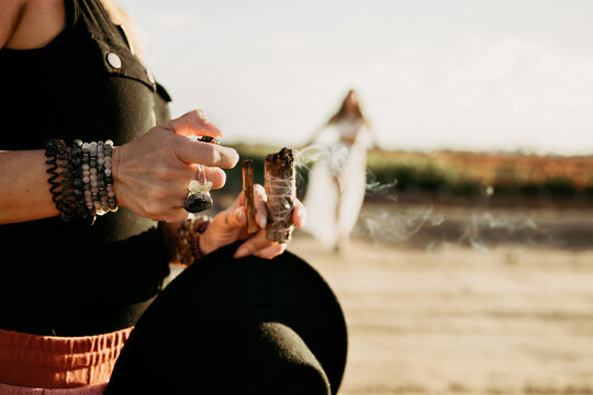 Woman lighting sage and palo santo in desert