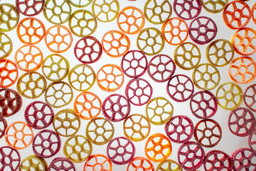 Background with texture dry italian pasta Rotelle. Different flavors and colors: egg, spinach,...