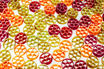 Background with texture dry italian pasta Rotelle. Different flavors and colors: egg, spinach,...