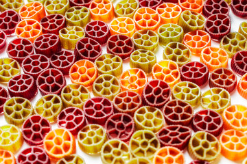 Background with texture dry italian pasta Rotelle. Different flavors and colors: egg, spinach,...