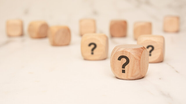 wooden blocks with question marks symbolizing uncertainty, decision-making, and strategic choices