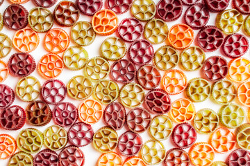 Background with texture dry italian pasta Rotelle. Different flavors and colors: egg, spinach, carrot, pepper.