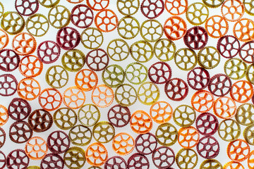 Background with texture dry italian pasta Rotelle. Different flavors and colors: egg, spinach, carrot, pepper.