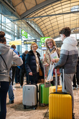 Teen boy and two women with colorful luggage at airport boarding gateTeen boy and two women with colorful luggage at airport boarding gate