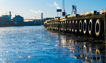 Obraz premium frozen harbor pier with reflections of industrial skyline.