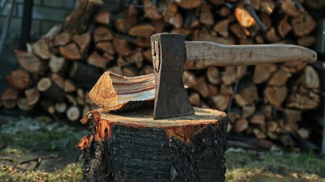 An axe with a wooden handle stuck in a wooden stump, harvesting firewood in the forest