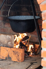 Cooking over an open fire in a rustic fireplace with bricks and glowing flames