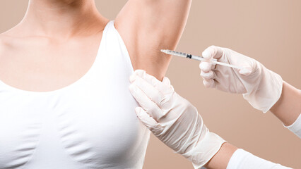 Woman receiving underarm treatment against hyperhidrosis. Armpit injections to prevent excessive...