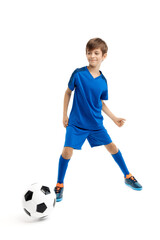 Diligent young boy in blue sport outfit playing with classic soccer ball over white background