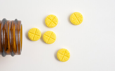 Yellow pills scattered on a white background with copy space.
