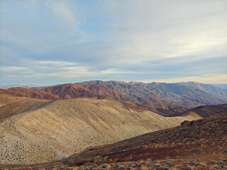 A breathtaking view of rolling desert hills bathed in golden light as the sun sets beyond the horizon.