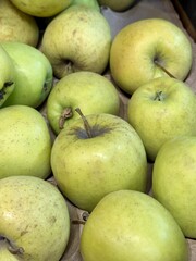 A mound of large green coloured apples in boxes is displayed in the window of the supermarket's vegetable stand, demonstrating organic, vegetarian and healthy food. Close-up