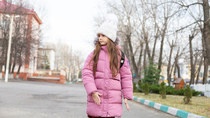Fototapeta premium Child girl wearing winter clothes with backpack outdoors go to school
