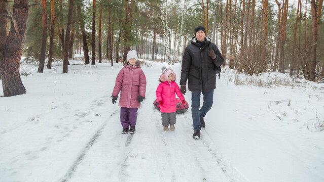 A child girl outdoor, winter time. Winter fun activity outdoor, winter vacation: riding on snow tubings. Family time