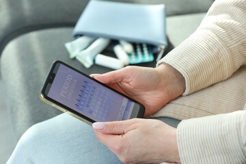 Menstruation. Woman using period calendar application on smartphone indoors, closeup
