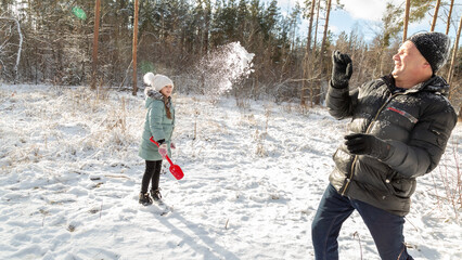 Playful family enjoying snowball fight in snowy winter park