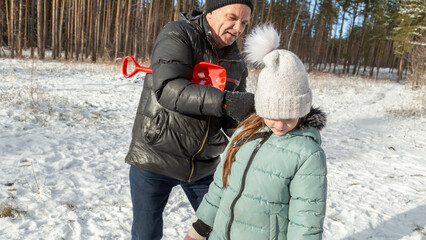 Little girls with her grandfather walk in a snowy forest, have fun together