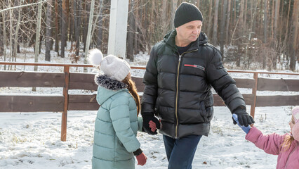 Little girls with her grandfather walking in park on snowy winter day