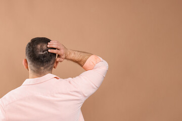 Baldness problem. Man with bald spot on beige background, back view. Space for text