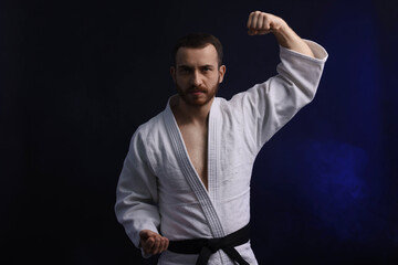 Man in uniform practicing karate on dark background