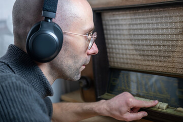 Positive Young man in wireless headphones, listen to old Vintage 60s radio, happily while listening...
