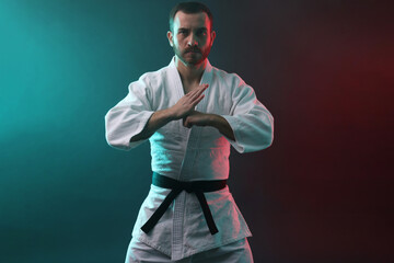 Karate fighter wearing uniform in color lights