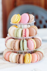 Fresh macarons in a four-tiered tray on a table.