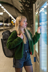 Girl with backpack stands on platform waiting for train in evening. Independent journey begins....