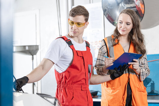 Male mechanic explains to female client cost of servicing car at auto service workshop