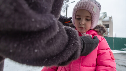 Grandmother with little girl granddaughter on snowy weather outdoors.