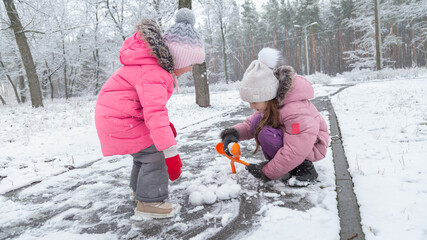 Active recreation with children in winter on cold days. Happy siblings having fun with snow