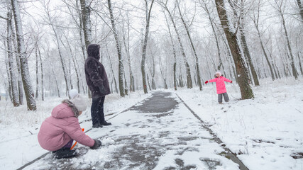 Grandmother with grandchildren in warm clothes playing outdoors in winter park, enjoying snowy...