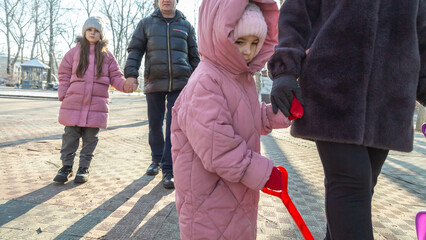 Grandparents walks with his granddaughters after school in the park in sunny winter day