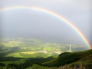 Obraz premium Stunning Rainbow Arcing Over Lush Green Landscape with Buildings, Nature, and a Tower.