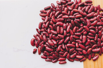 A vibrant collection of red kidney beans is displayed on a wooden surface, showcasing their smooth texture and deep color. The arrangement highlights their natural beauty and freshness