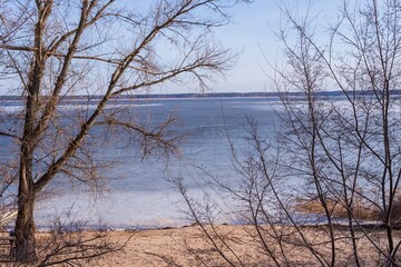Beautiful landscape of a frozen river in early spring. First thawed patches. Sunny spring day