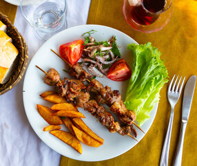 Lamb shish kebab with lettuce, tomatoes and French fries. Turkish cuisine
