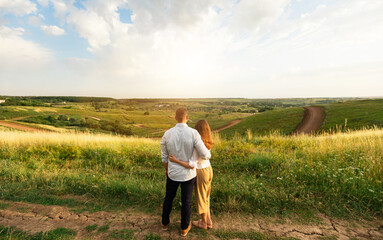 Togetherness Concept. Back view of two lovers standing in field, hugging and looking at landscape, copy space