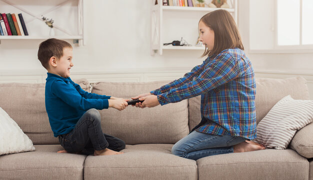 Siblings fighting over remote control at home, brother and sister have quarrel, copy space