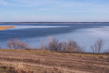 Beautiful landscape of a frozen river in early spring. First thawed patches. Sunny spring day