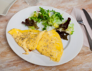 Tender omelet with vitamin salad of fresh lettuce for healthy breakfast served on white plate..