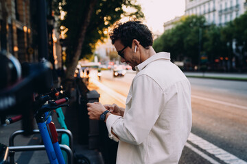 young traveler smiles while taking a selfie in front of historic building, capturing the beauty of the city's architecture at golden hour. His relaxed posture reflects joy and appreciation for travel