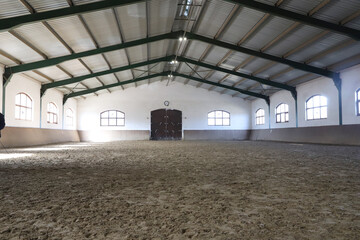 View in an indoor riding hall for horses and riders. The riding school is suitable for dressage and jumping horses.Empty riding arena is suitable for riders © acceptfoto