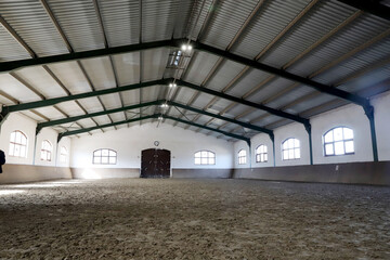 View in an indoor riding hall for horses and riders. The riding school is suitable for dressage and jumping horses.Empty riding arena is suitable for riders