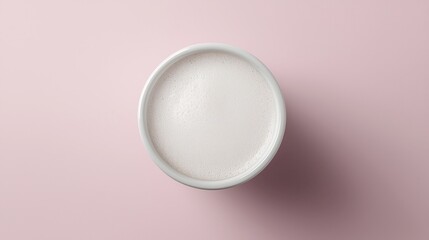 Top view of frothy beverage in white cup on pink background.