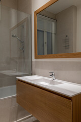 Warm contemporary bathroom with a large mirror, wooden vanity, and a soft-lit modern interior